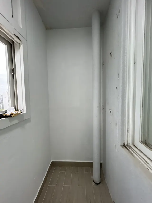 흰색으로 도장된 베란다 벽과 배관 기둥, 우드 느낌 타일 바닥