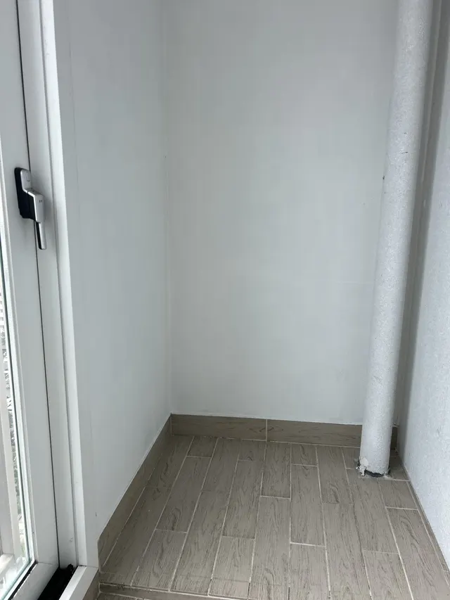 베란다 벽 흰 베란다 벽과 창 손잡이, 우드 타일 바닥, 배관 기둥