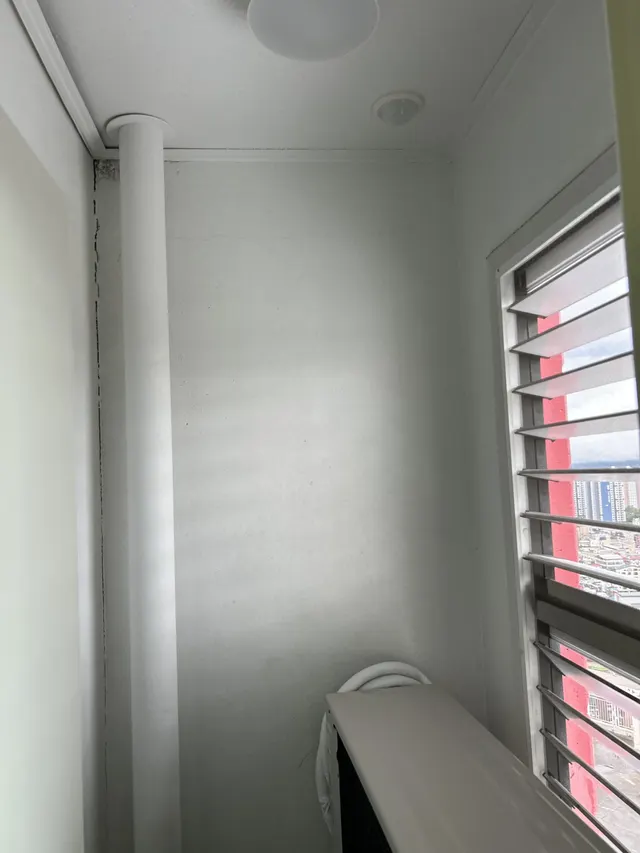 베란다 벽 흰 도장 베란다 벽과 배관 기둥, 루버창이 보이는 모습